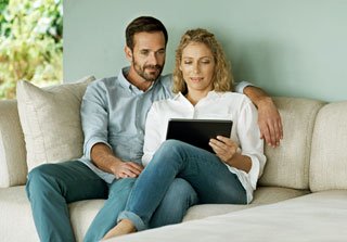 Couple sitting on a sofa looking at a computer