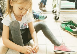 Niña rubia atándose los cordones de la zapatilla