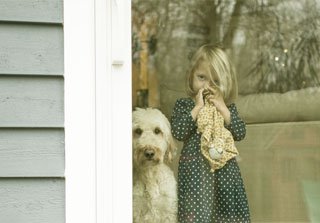 Niña y perro tras un ventanal