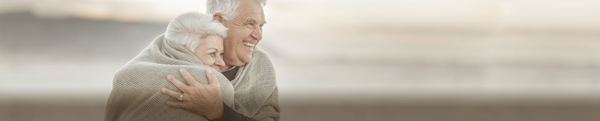 Pensioners covered by a blanket and embracing